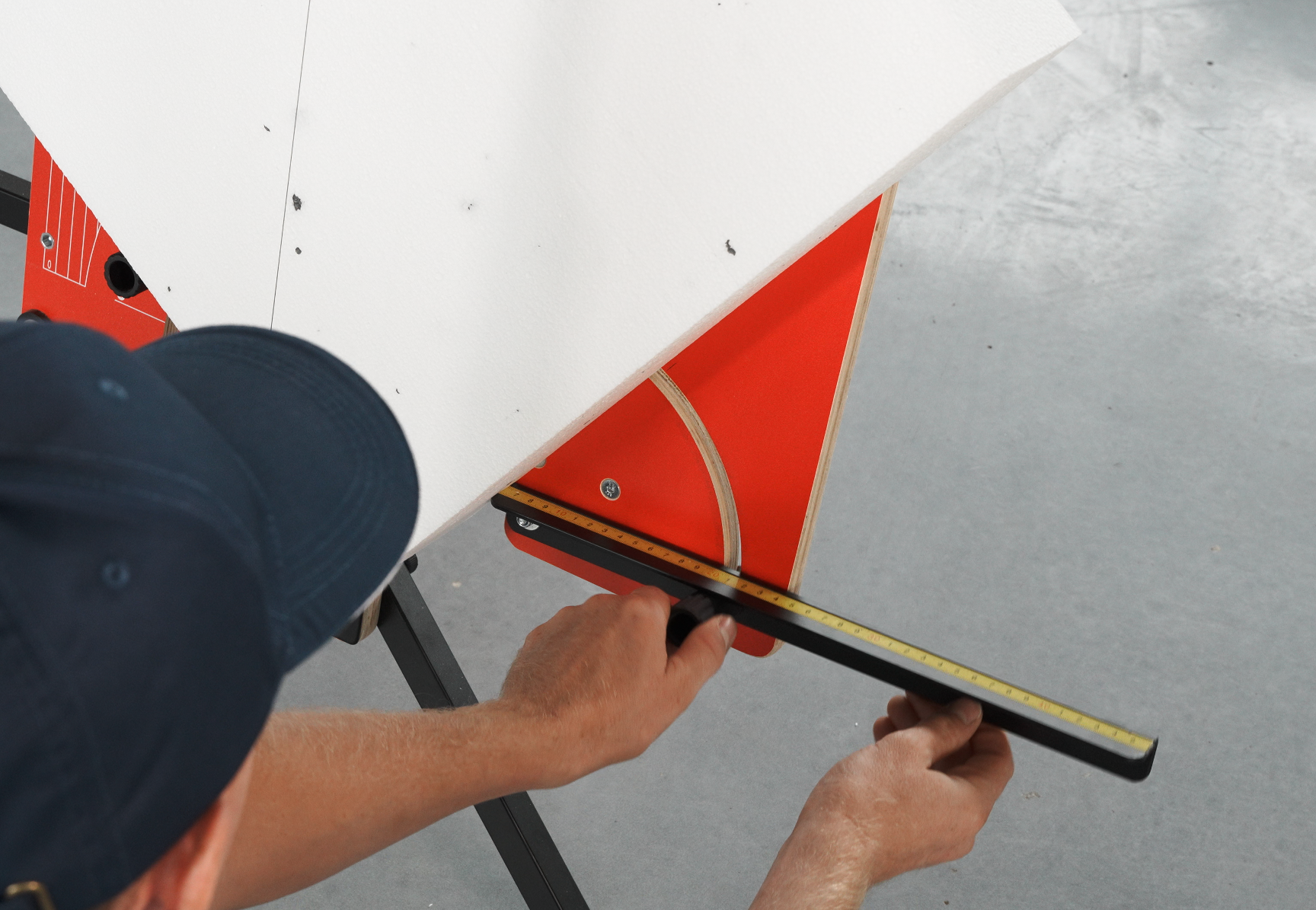 Człowiek odmierzający styropian linijką na maszynie do wycinania w styropianach.